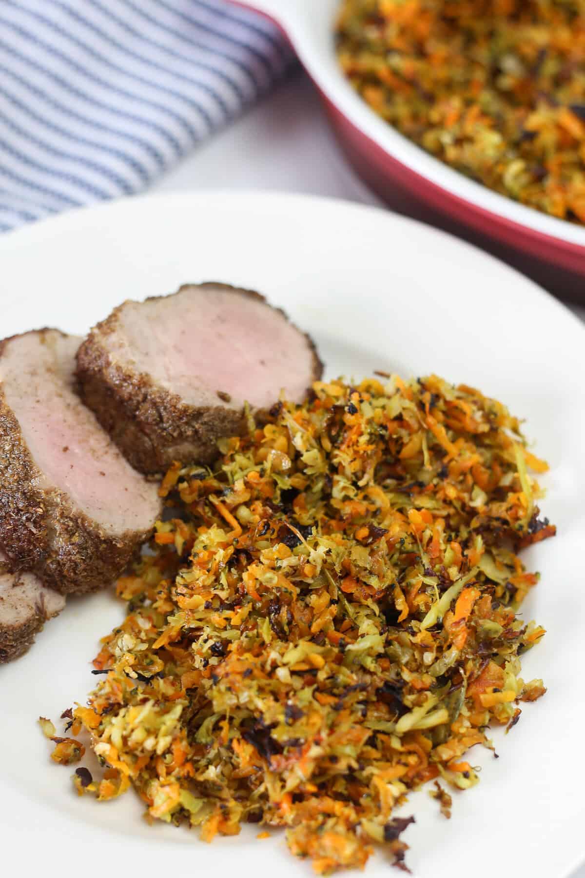 Slices of pork tenderloin with a serving of roasted vegetable hash on a plate.
