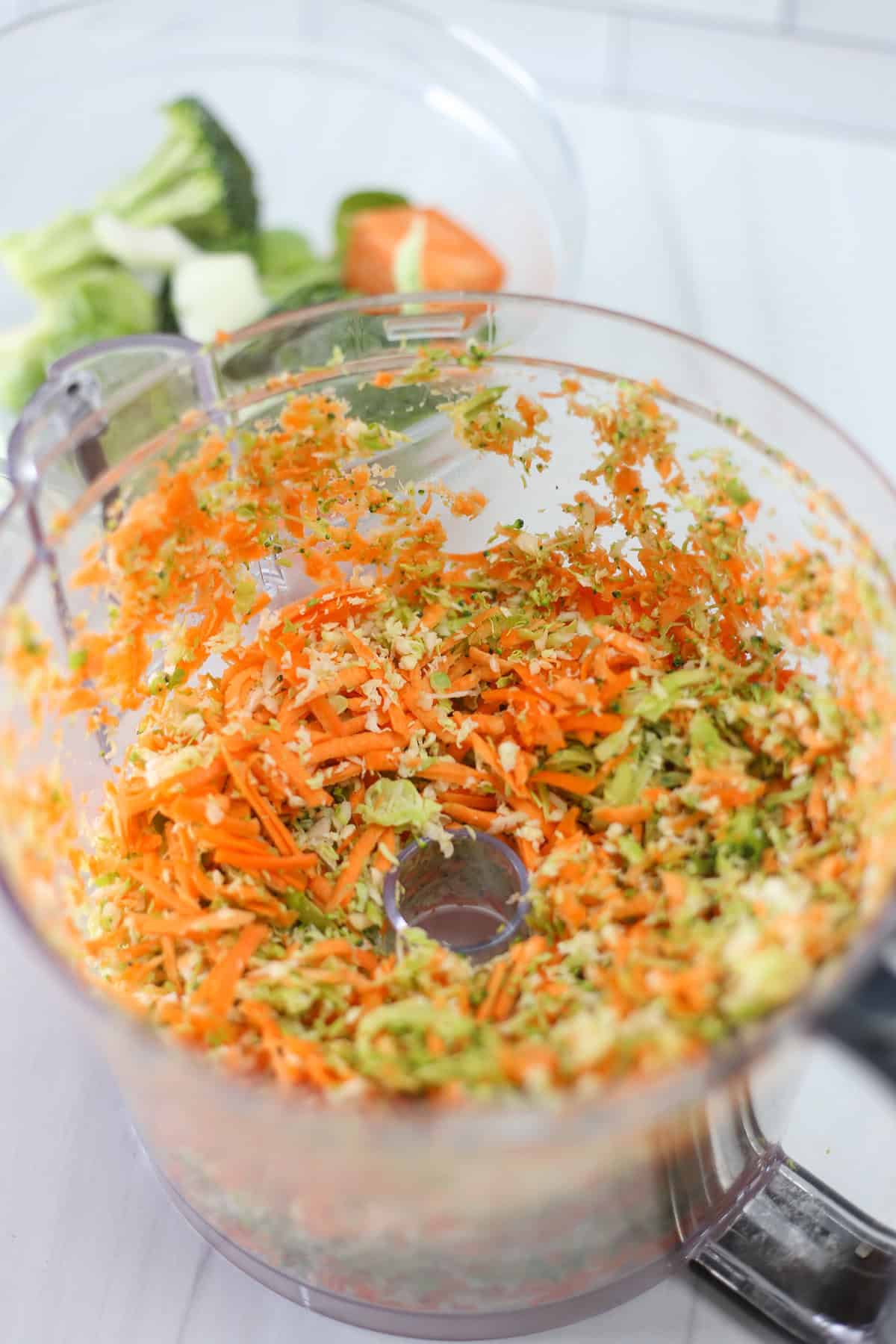 A food processor bowl with shredded vegetables in it.