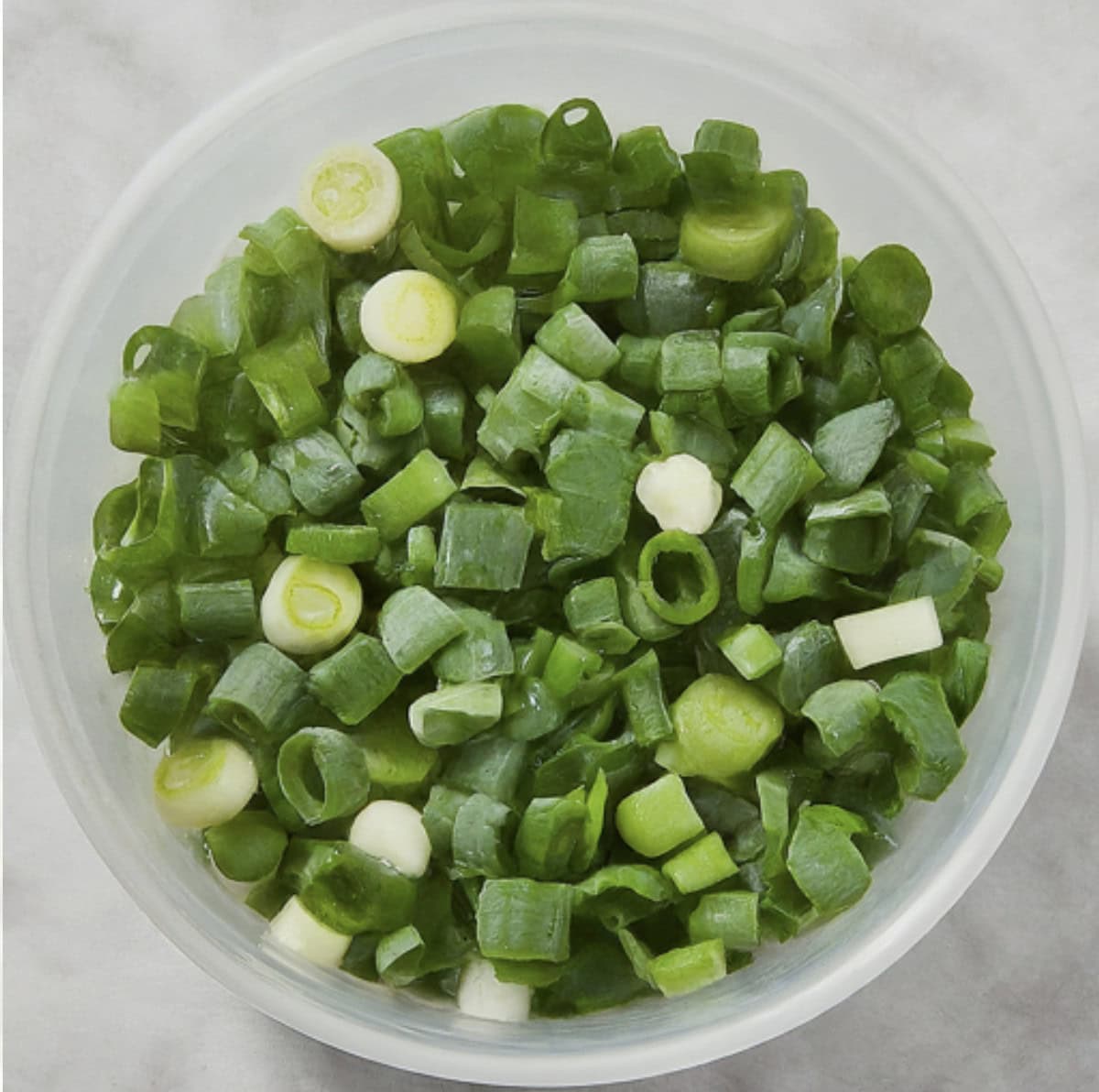 A container filled with chopped, frozen green onions. 