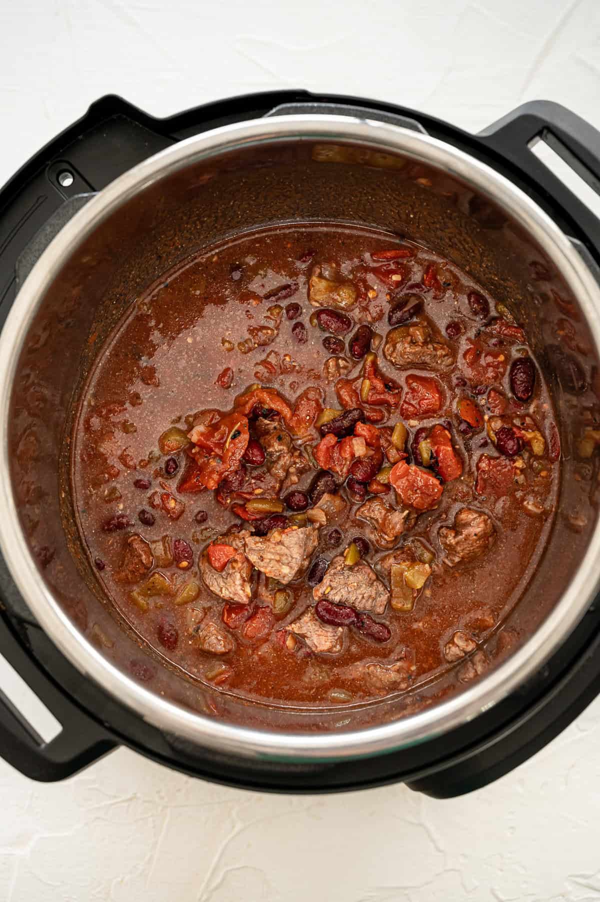 Ingredients for Steak Chili dumped in an Instant Pot ready to be cooked.