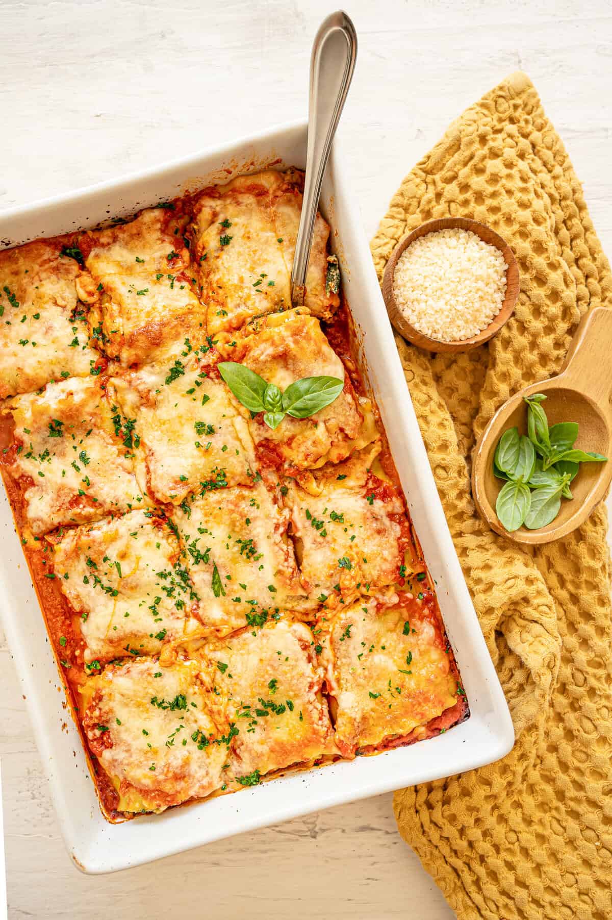 Spinach lasagna roll-ups in a white casserole dish with chopped fresh parsley on top.