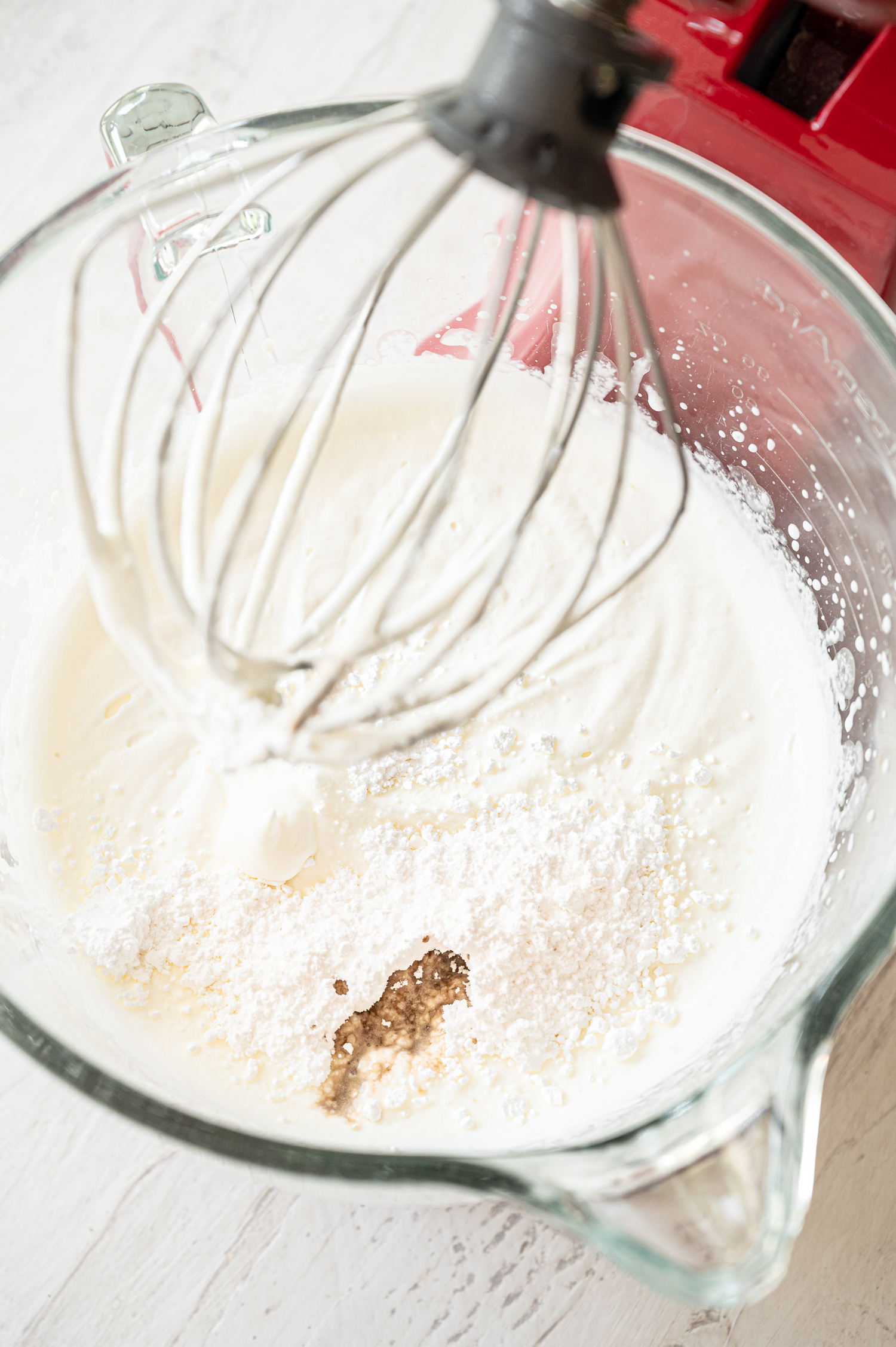 Heavy whipping cream, powdered sugar, and vanilla ready to whipped in a mixing bowl.