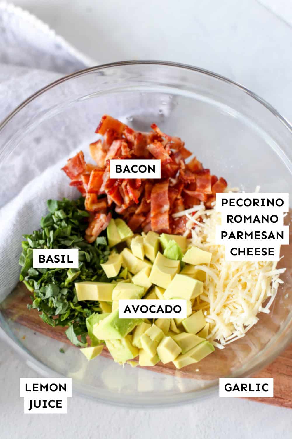 Avocado basil and bacon pasta ingredients in piles in a bowl.
