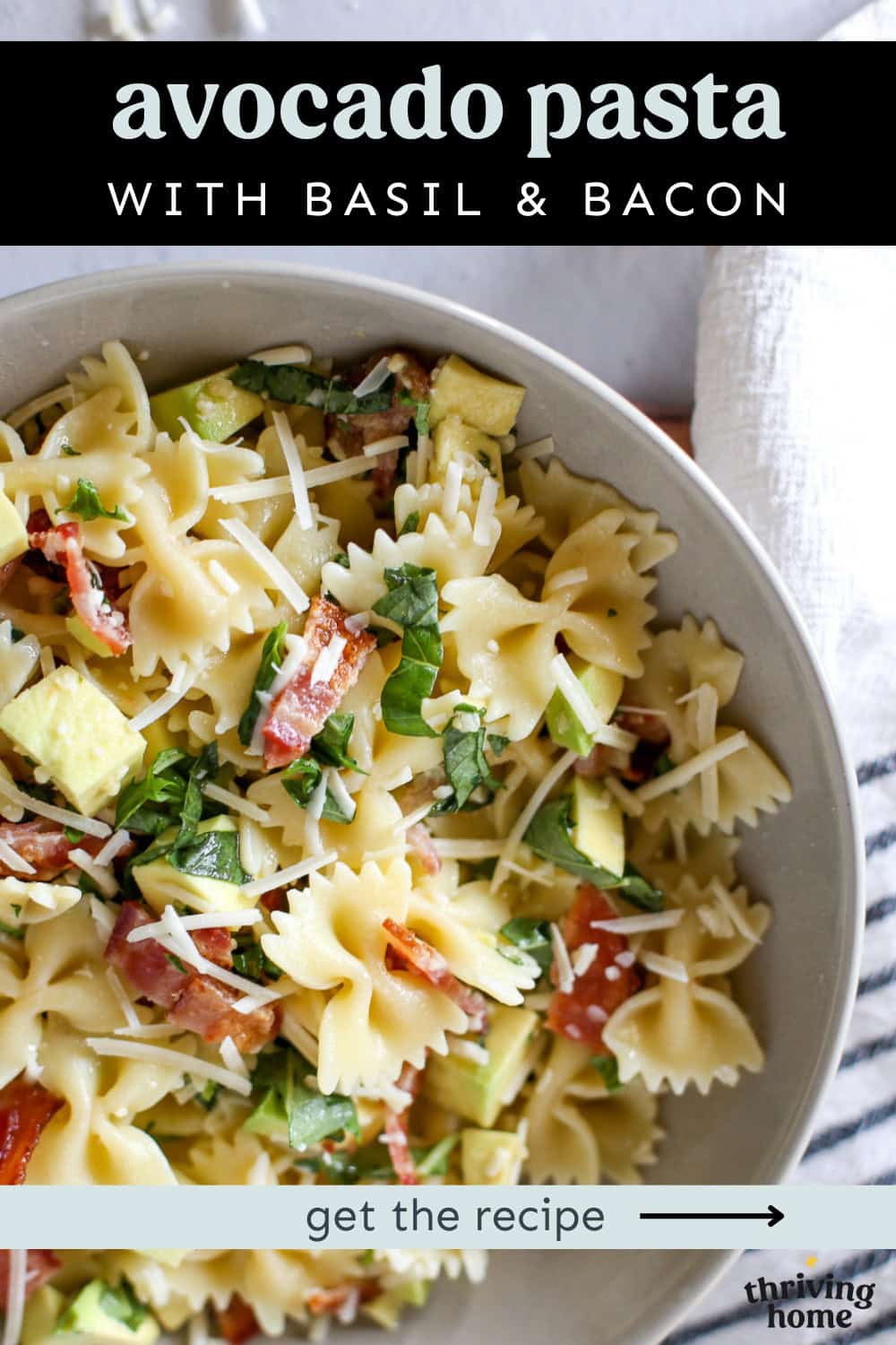 Avocado pasta with basil and bacon in a white bowl with shredded Parmesan on top.