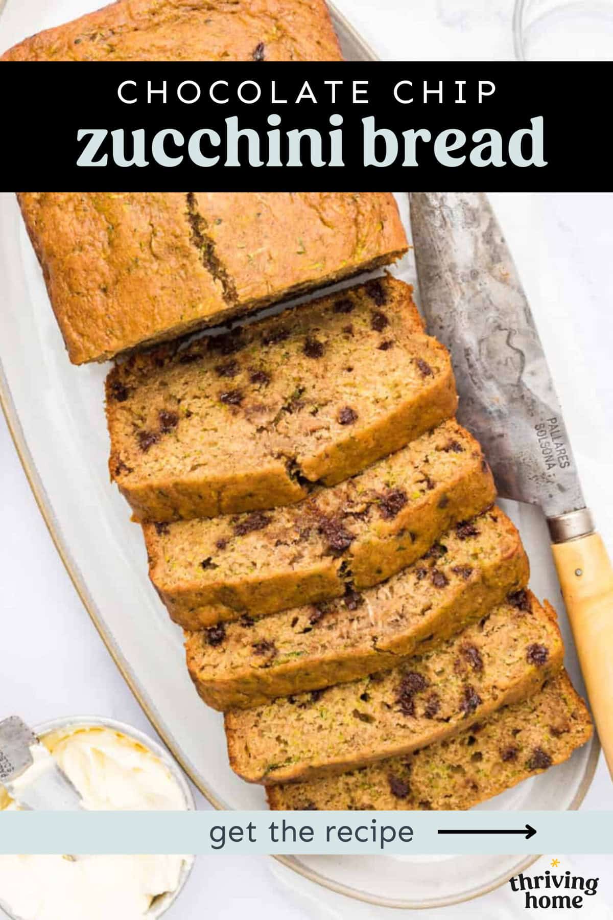 Chocolate chip zucchini bread on a platter with half it sliced and a small bowl of butter on the side.
