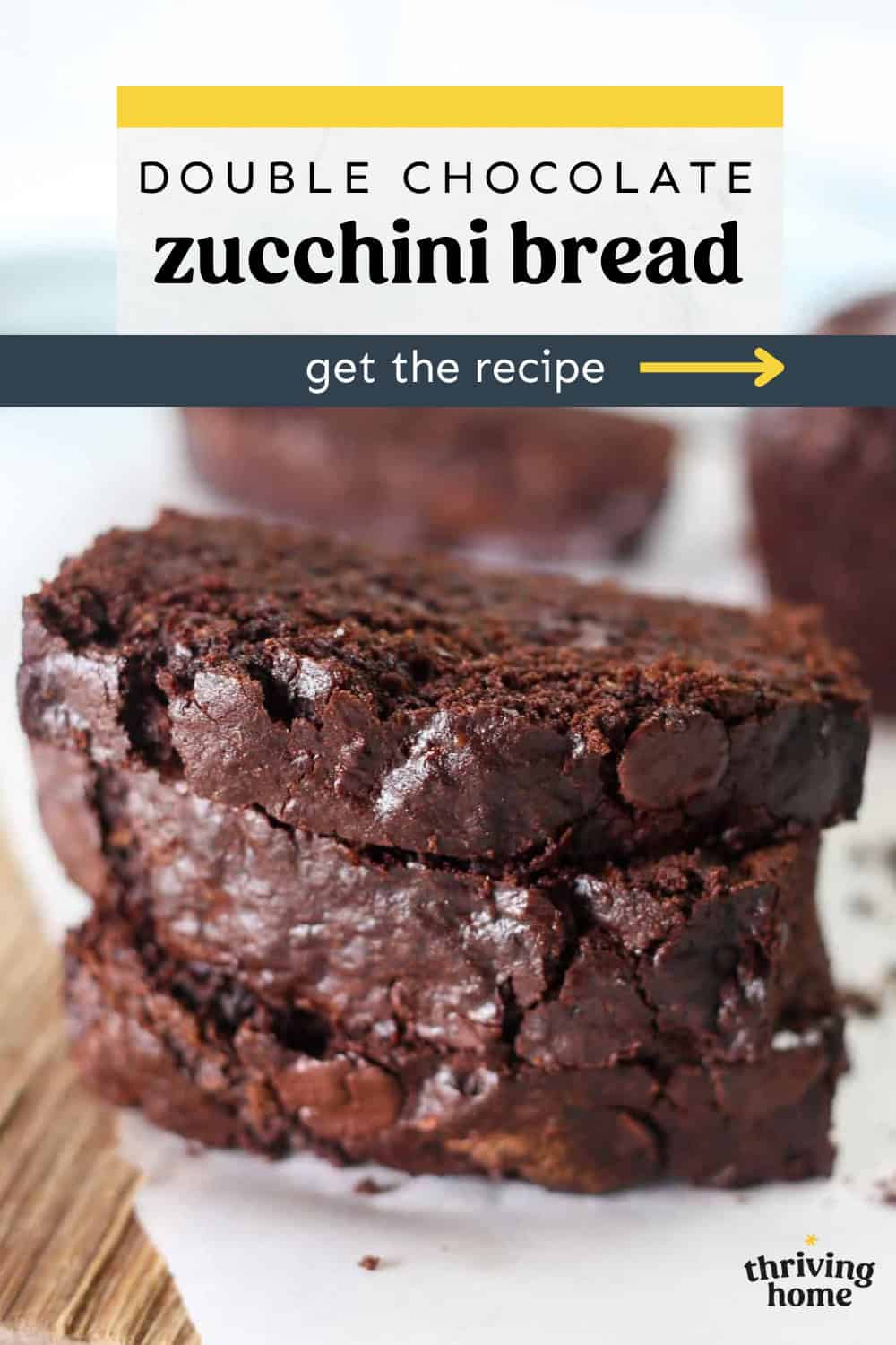 Three slices of double chocolate zucchini bread stacked up on a wooden cutting board.