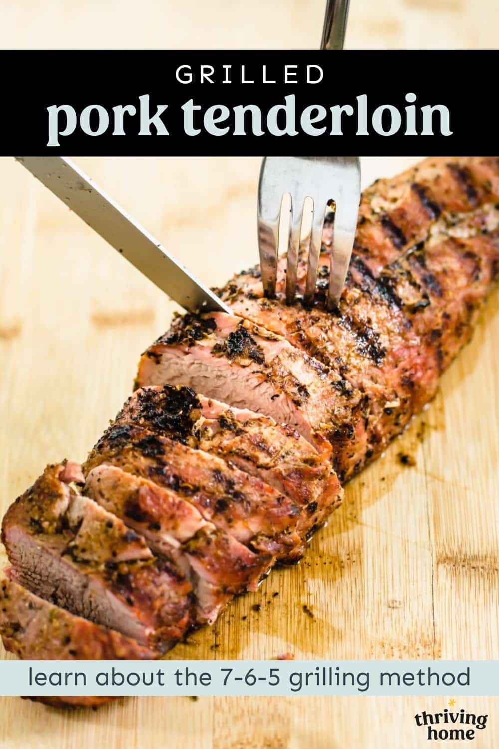 Grilled pork tenderloin on a wooden cutting board being sliced with a fork and knife.