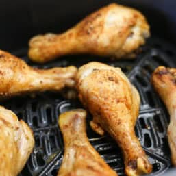 Crispy chicken drumsticks still in the air fryer basket they were cooked in.