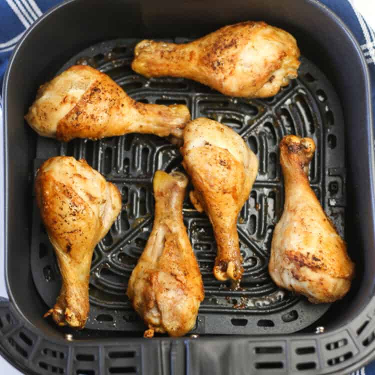 Chicken drumsticks in an air fryer basket just finished cooking.