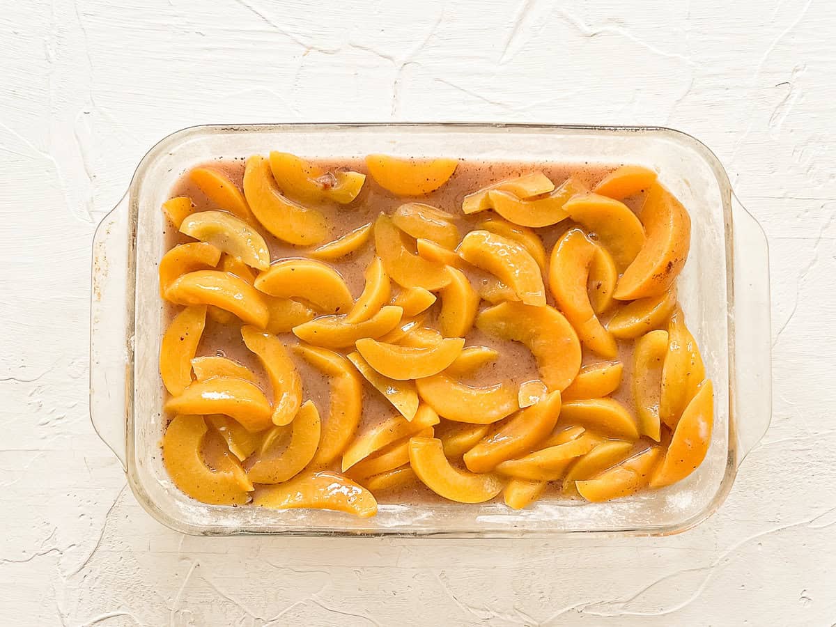 Canned peaches with cornstarch and spices mixed in and spread out in a 9x12 baking dish.