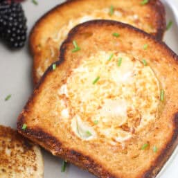 Egg in a hole on a plate with fruit.