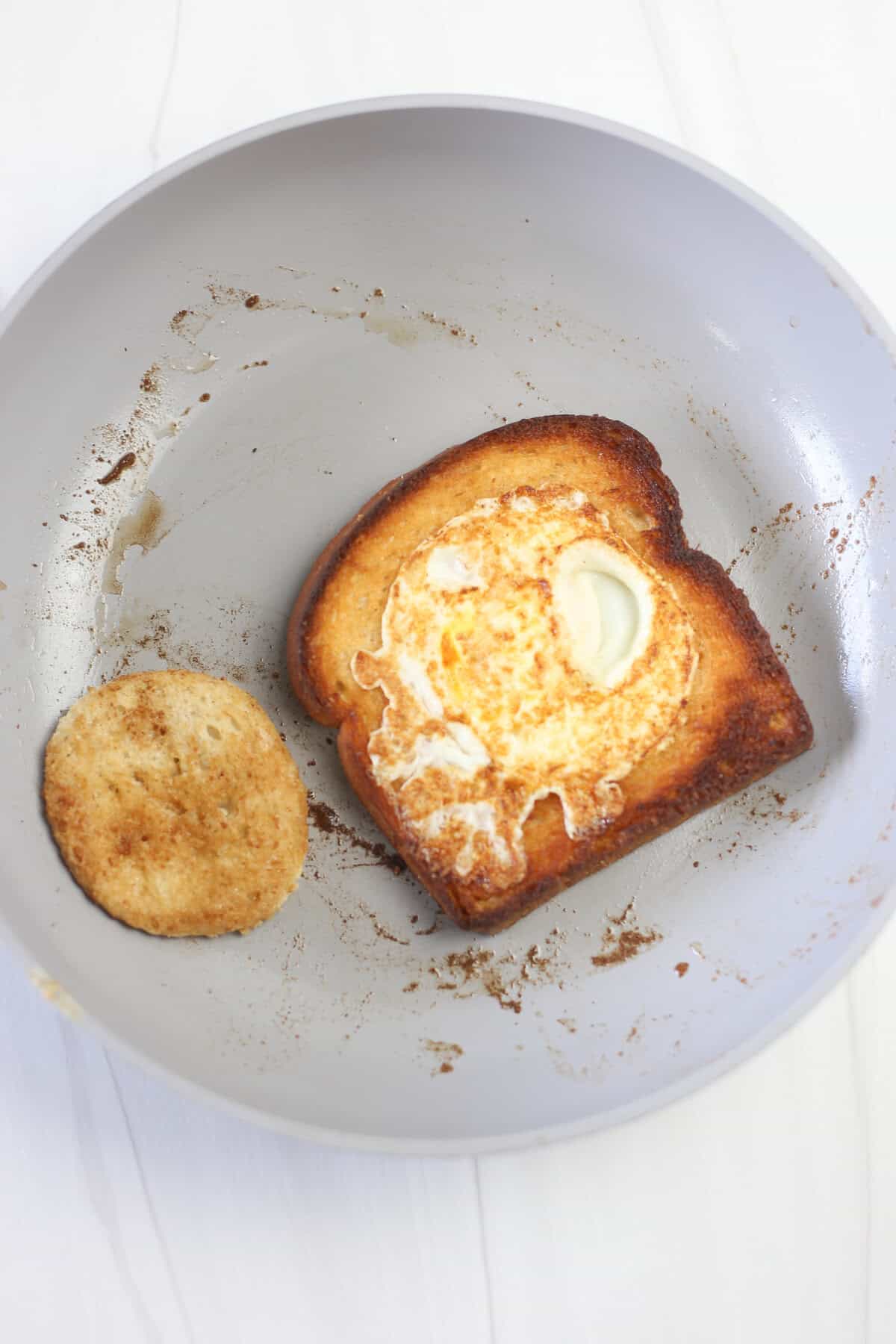 A fully cooked egg in a hole on a skillet. 