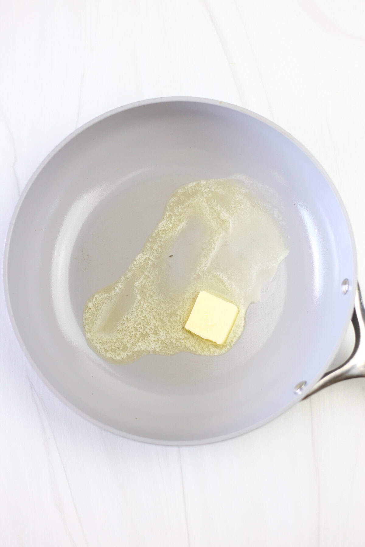 A tablespoon of butter being melted in a skillet. 