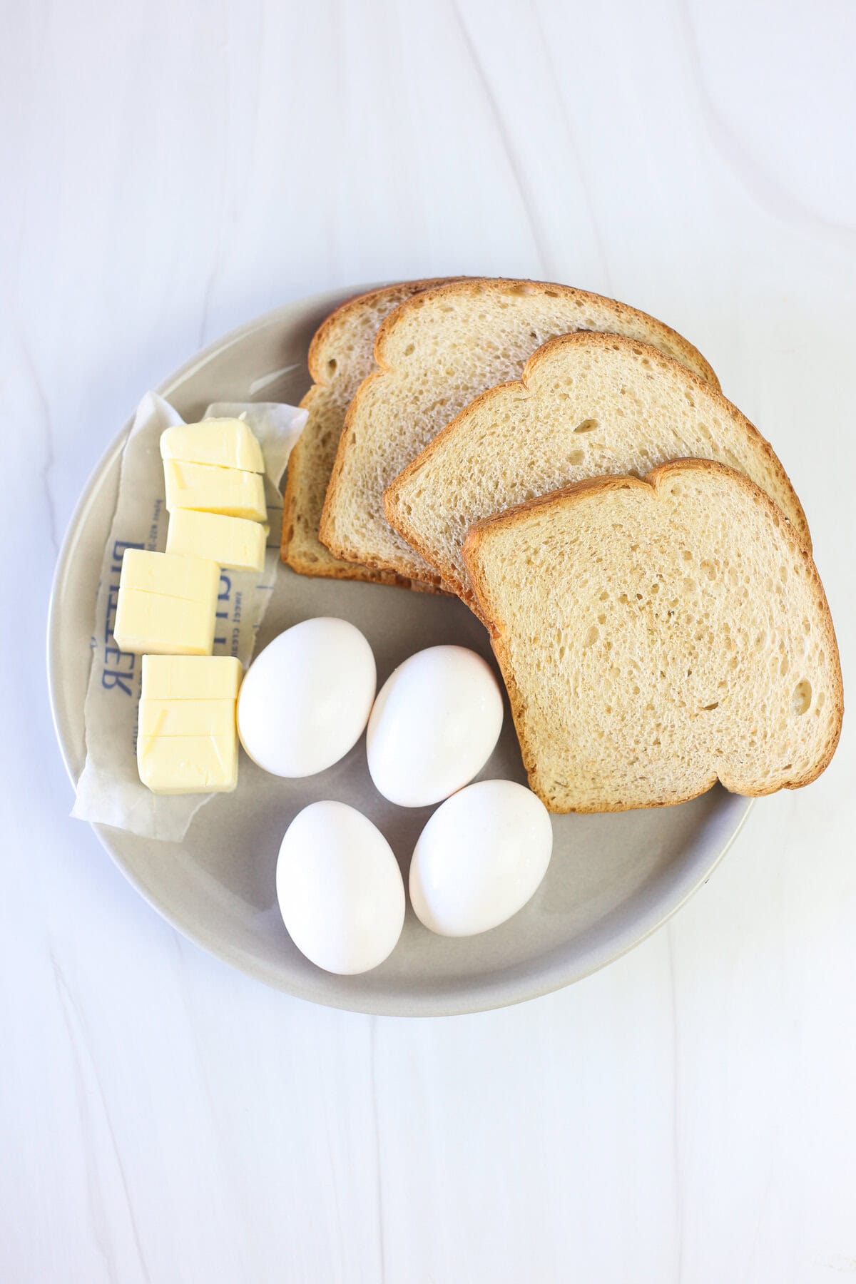 Bread, eggs, and butter on a plate. 