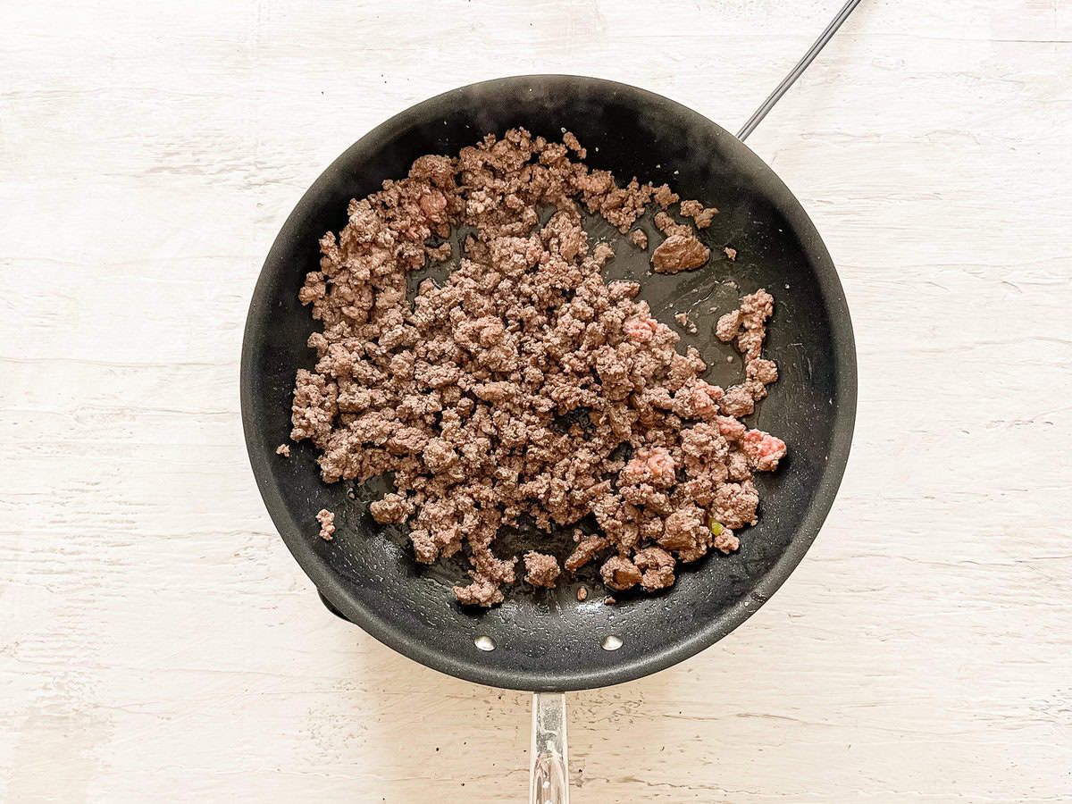Ground beef sauteing in a skillet.