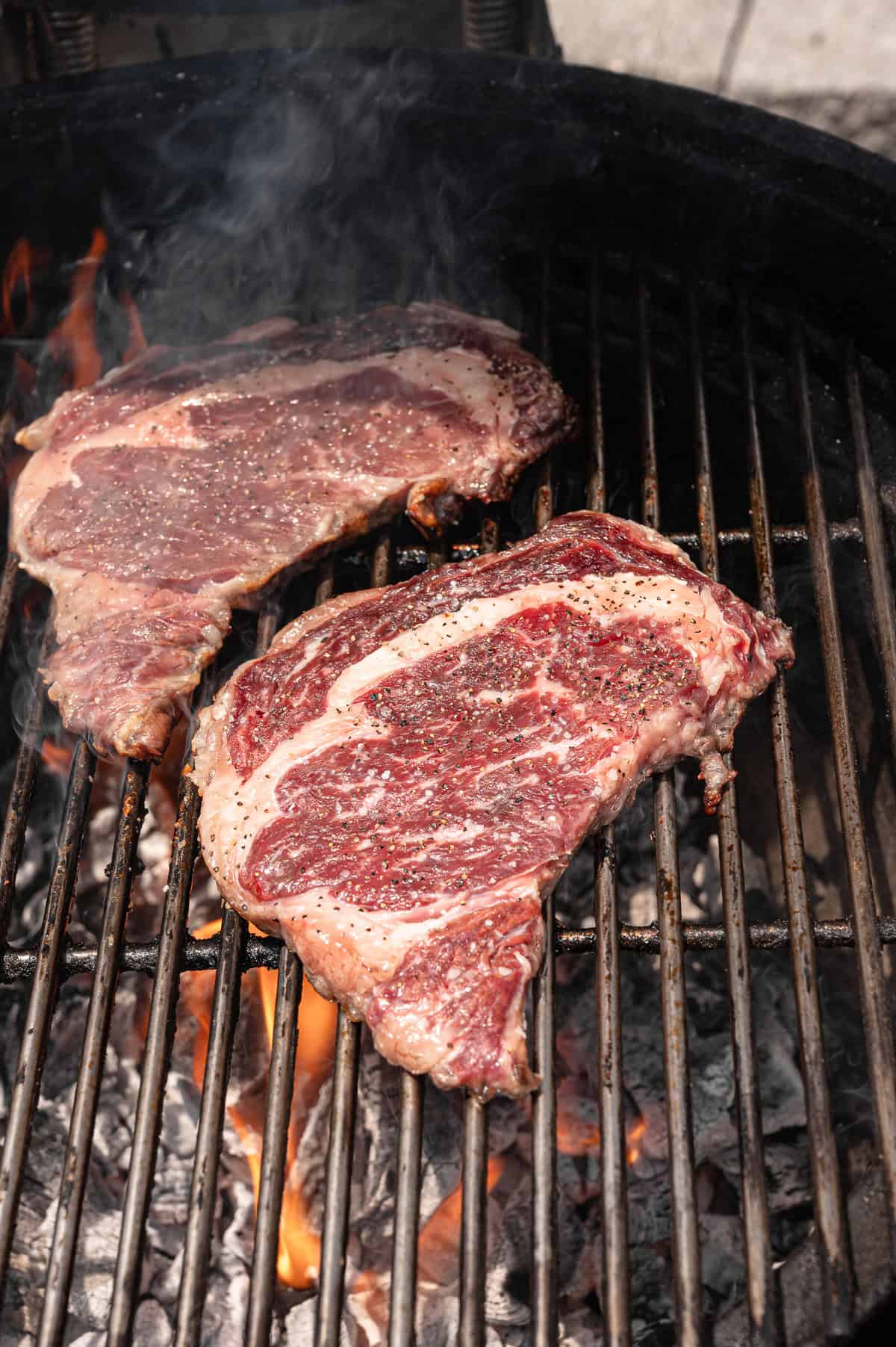 Steaks on a grill partially cooked.