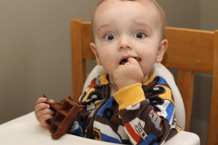 Baby eating a chocolate waffle.