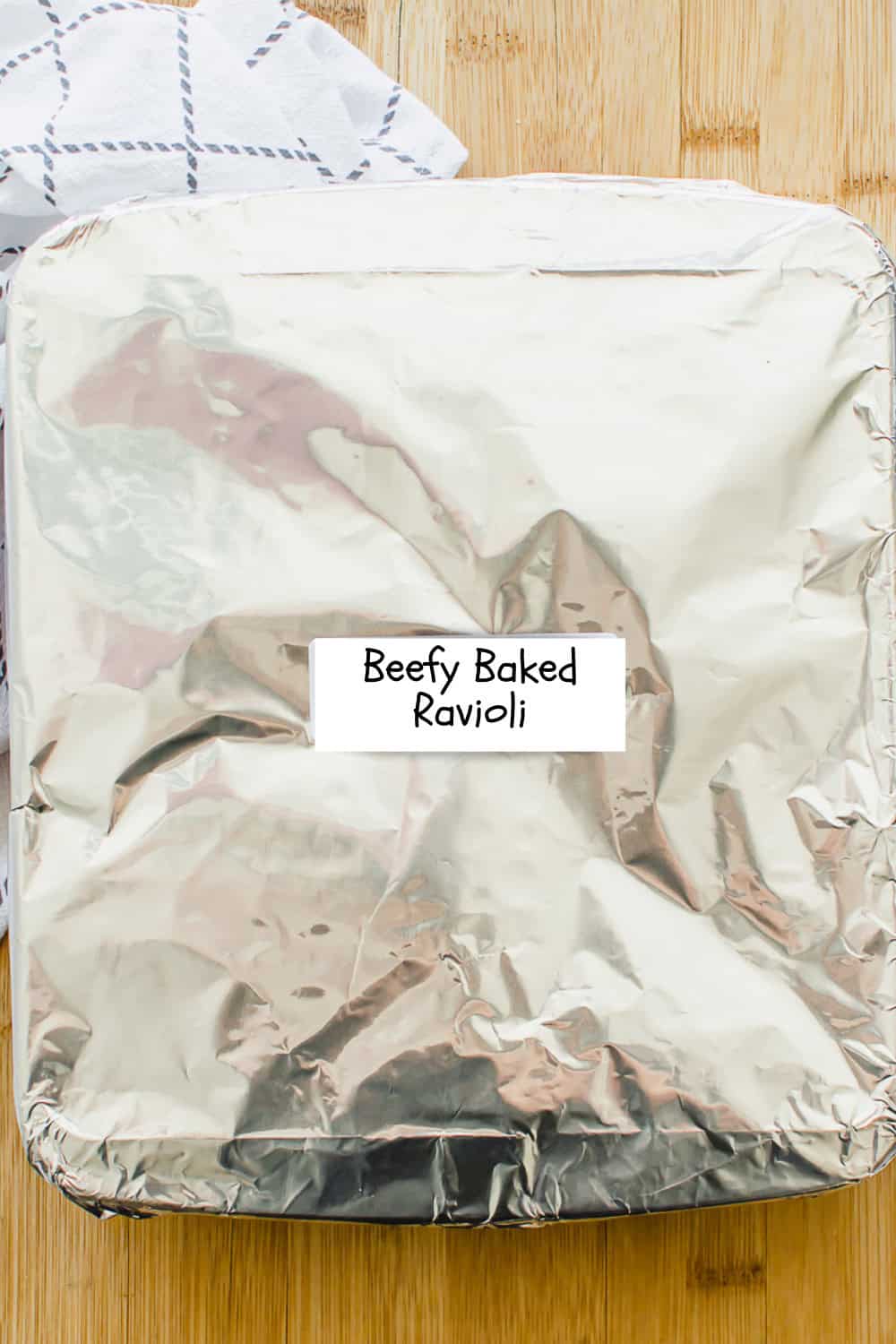 8x8 baking dish covered in foil labeled Beefy Baked Ravioli.