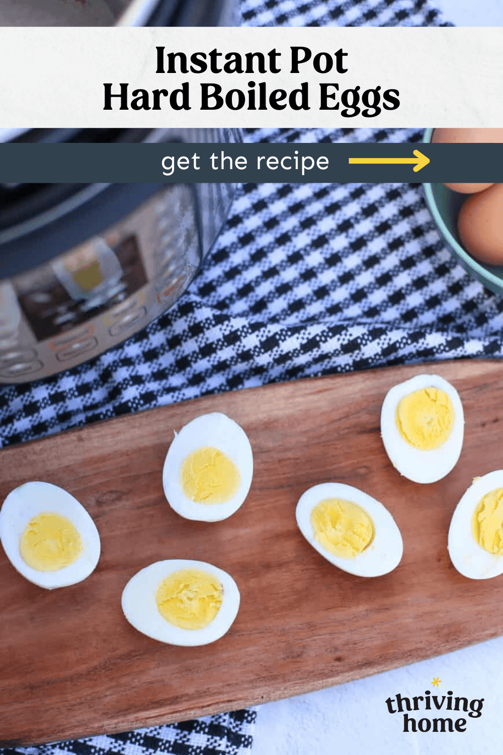 Boiled eggs cut in half on a wooden cutting board in front of an Instant Pot.