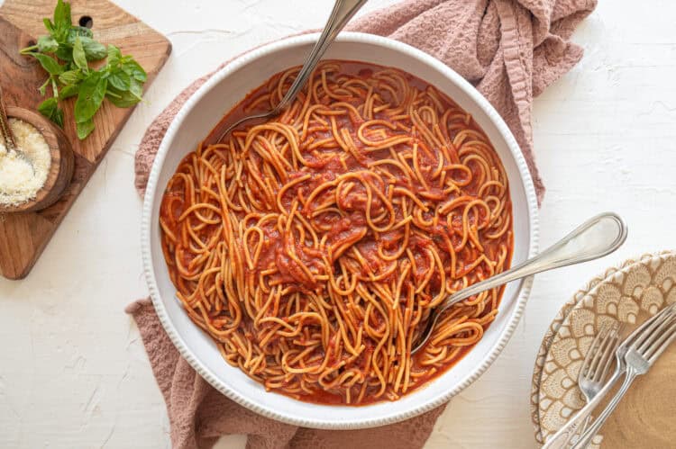 Instant Pot spaghetti in a white serving bowl with garlic bread on the side.