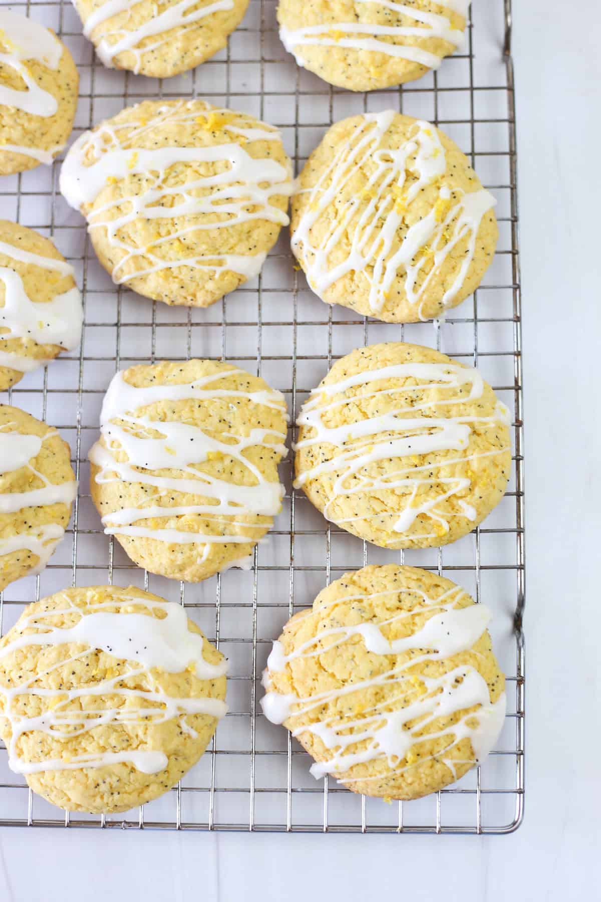 Glaze drizzled over lemon poppyseed cake mix cookies on a baking rack.