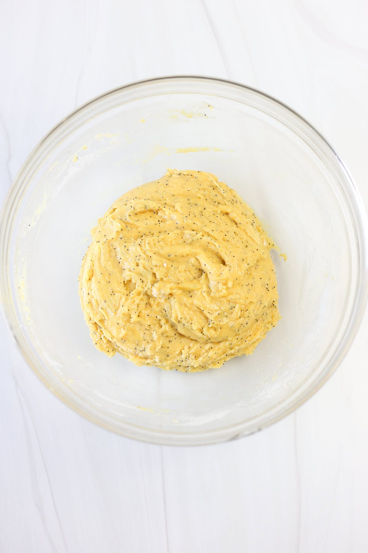 Lemon poppyseed cake mix cookie dough in a glass mixing bowl.