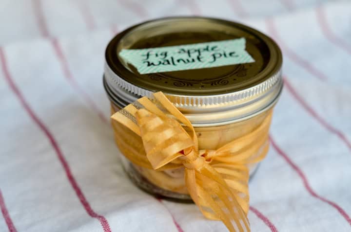 Mini mason jar with a gold ribbon wrapped around it and a cute label saying Fig Apple Walnut Pie.