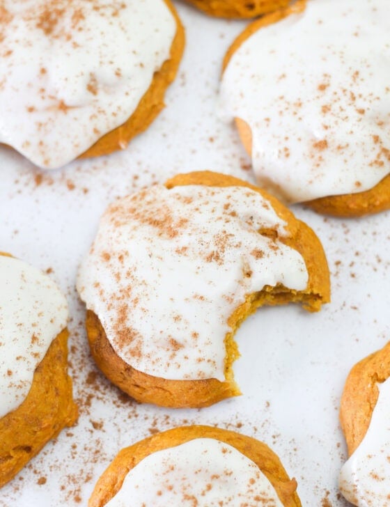 Pumpkin spice cake mix cookies lined up on parchment paper with icing on top.