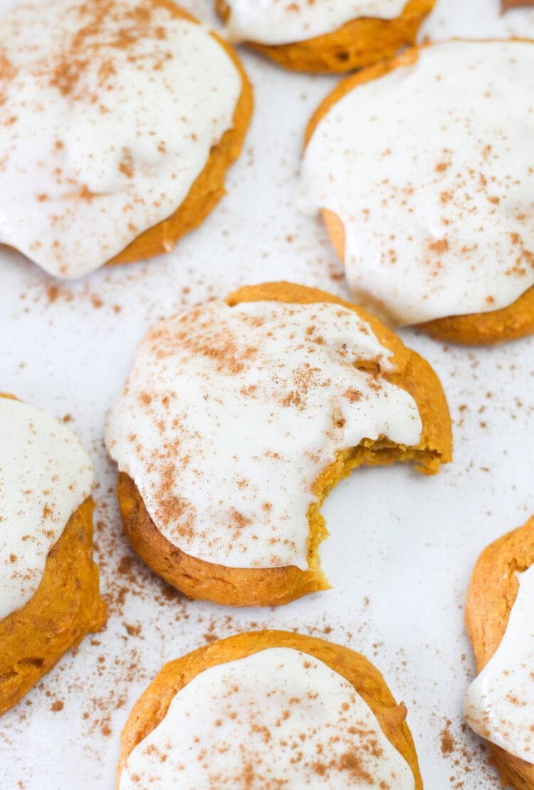 Pumpkin spice cake mix cookies lined up on parchment paper with icing on top.