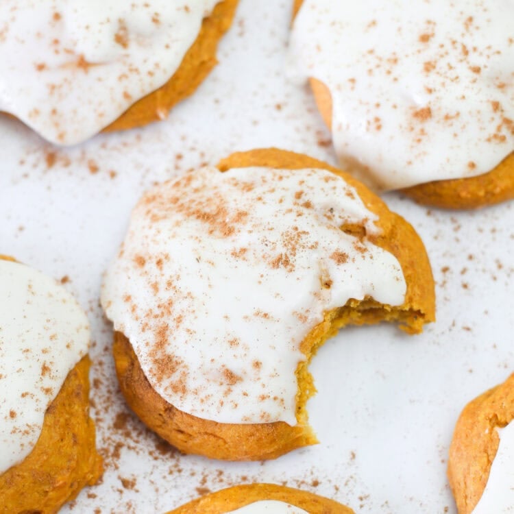 Pumpkin spice cake mix cookies lined up on parchment paper with icing on top.