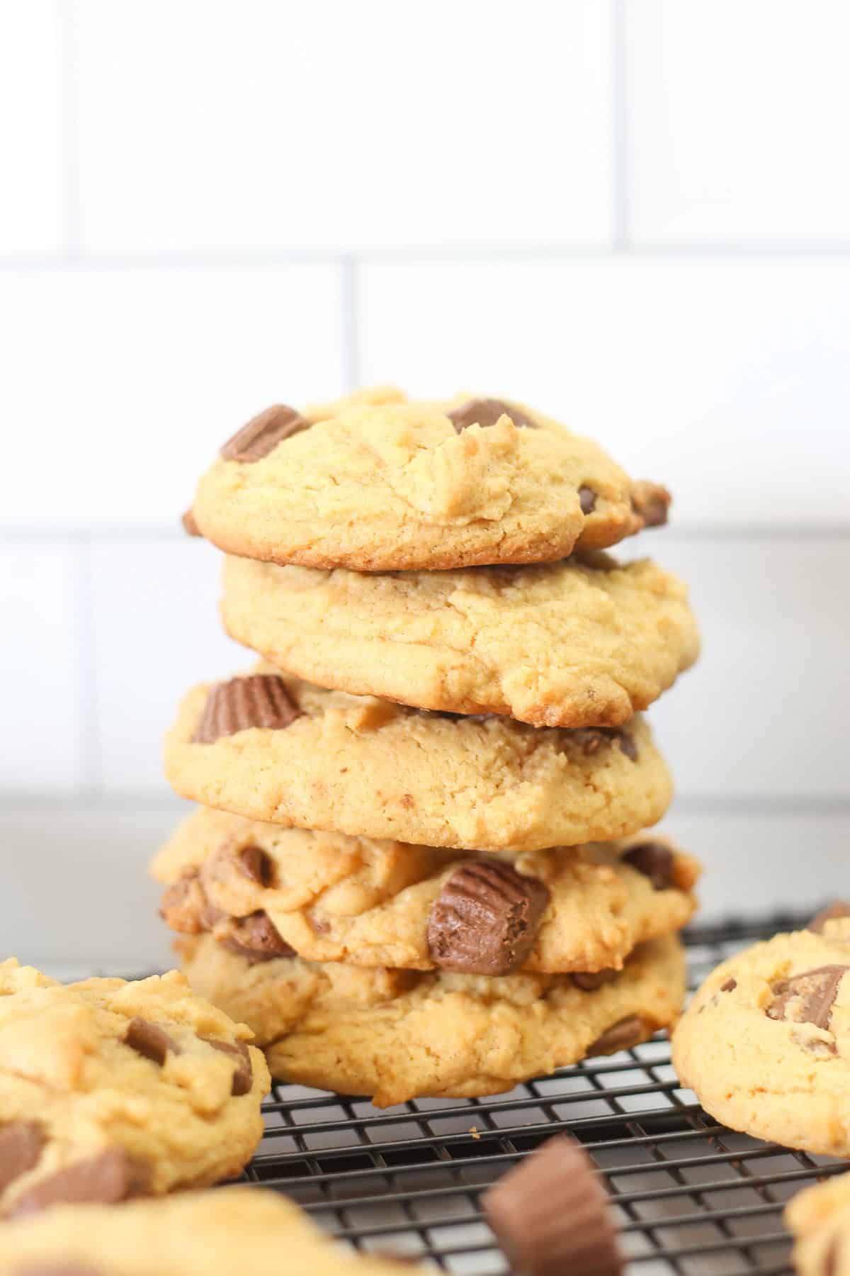 Five Reese's peanut butter cup cake mix cookies stacked up on a baking rack.