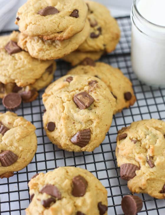 Reese's peanut butter cup cake mix cookies stacked around a baking rack with a glass of milk.