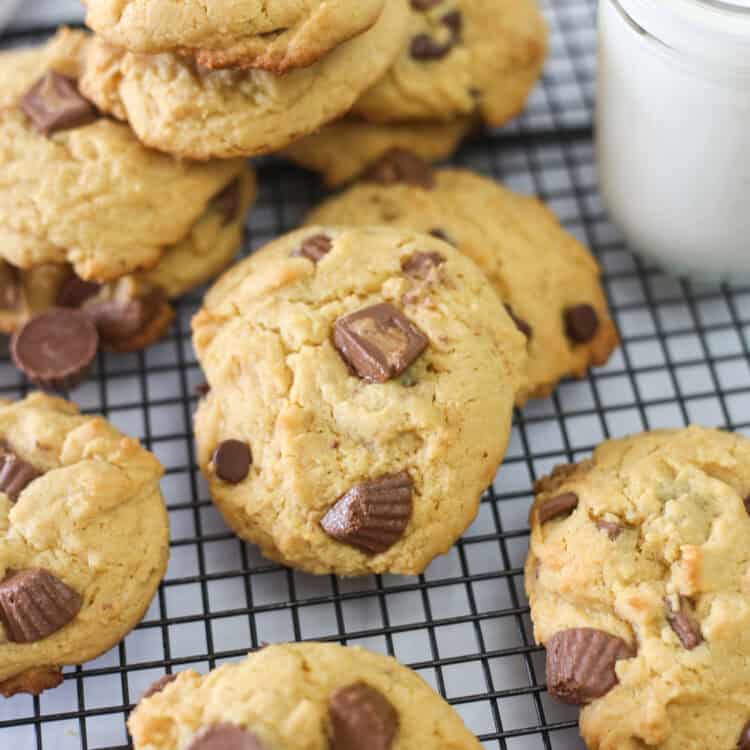 Reese's peanut butter cup cake mix cookies stacked around a baking rack with a glass of milk.