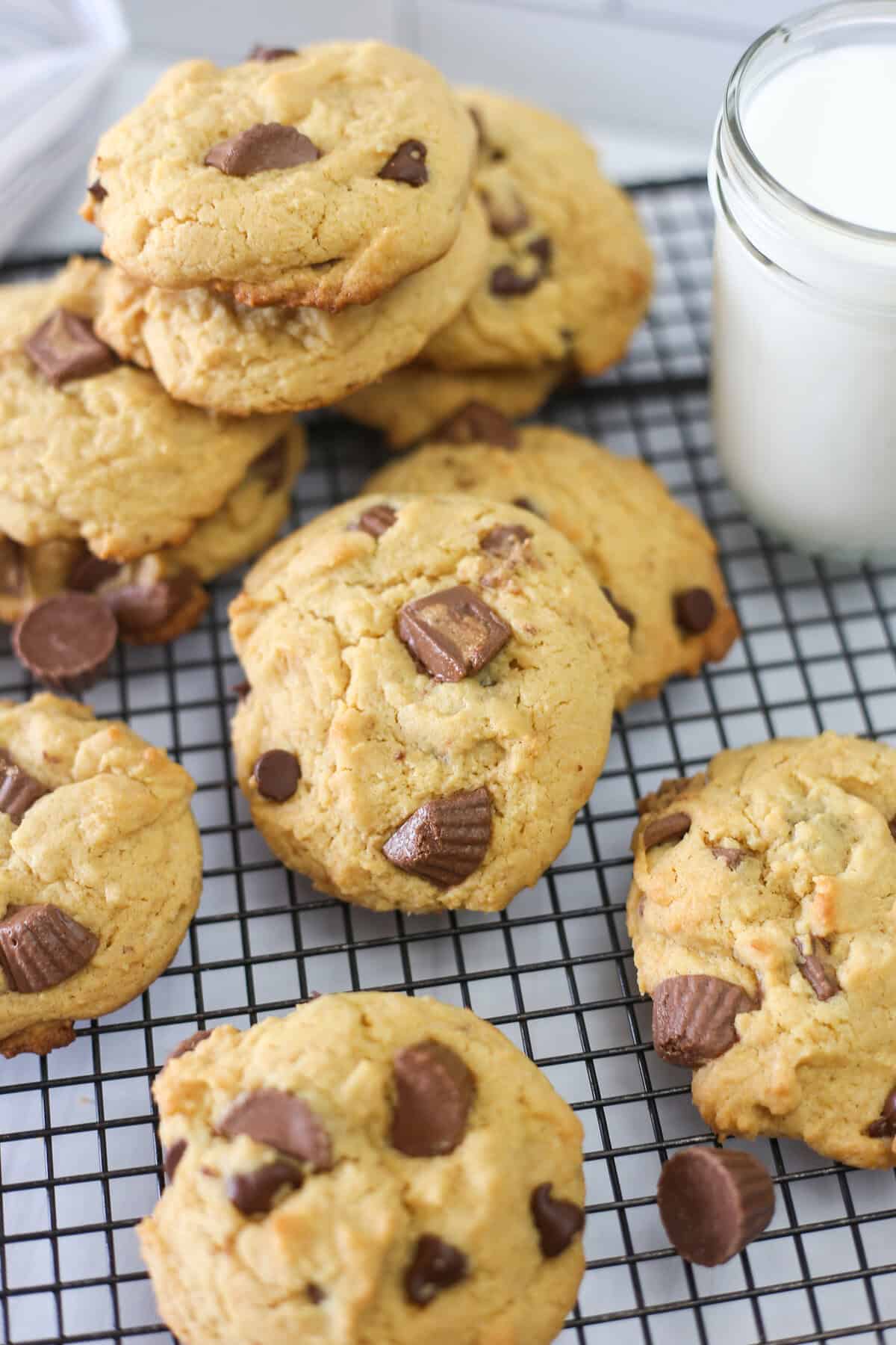 Reese's peanut butter cup cake mix cookies stacked around a baking rack with a glass of milk.