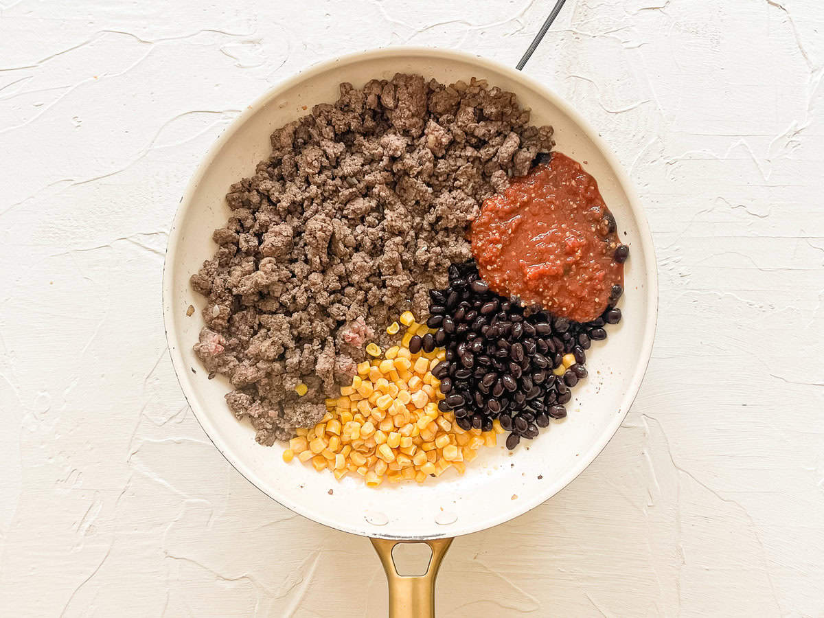 A skillet with ground beef, salsa, corn, and black beans ready to mix for inside quesadillas.