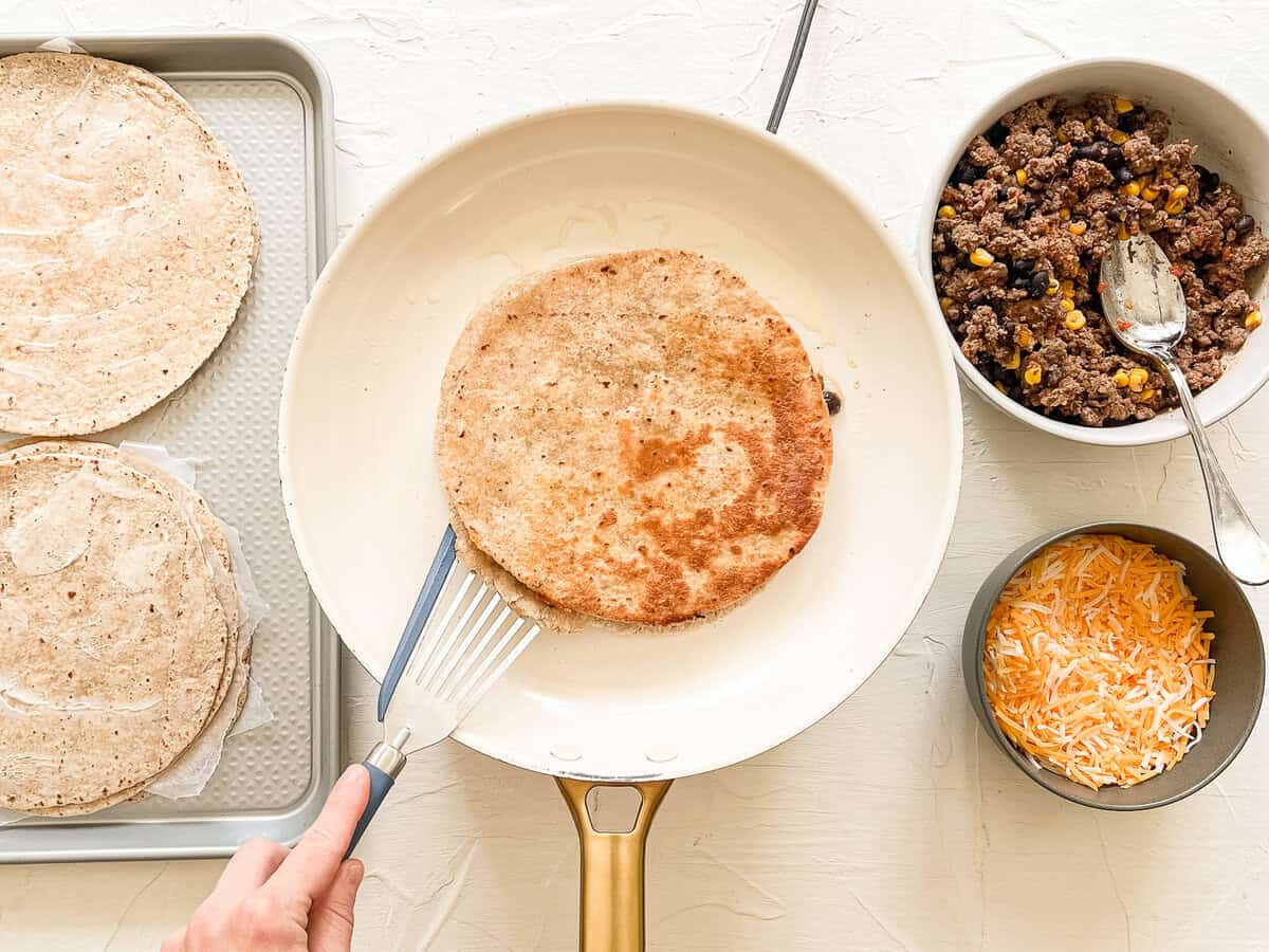 Quesadilla station with a spatula flipping a quesadilla in a skillet in the middle.