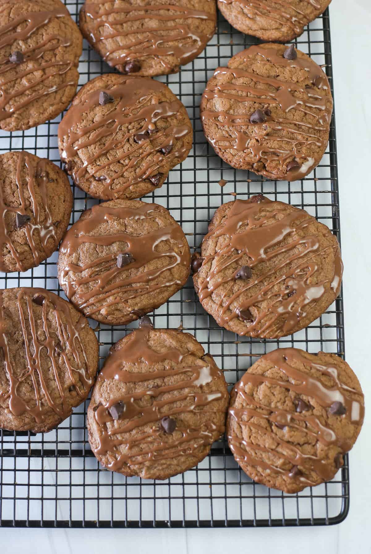 Nutella cake mix cookies lined up on a baking rack with a Nutella glaze drizzled on top.