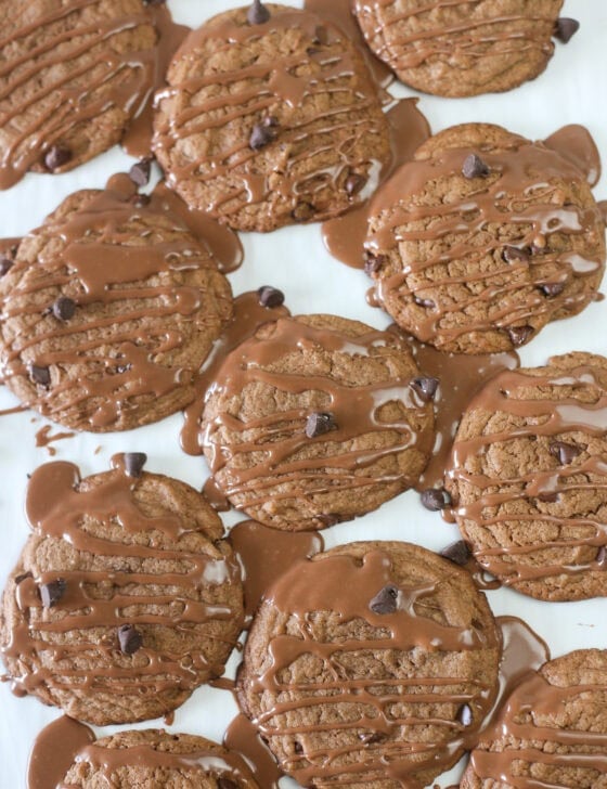 Nutella cake mix cookies on parchment paper drizzled with a Nutella glaze.