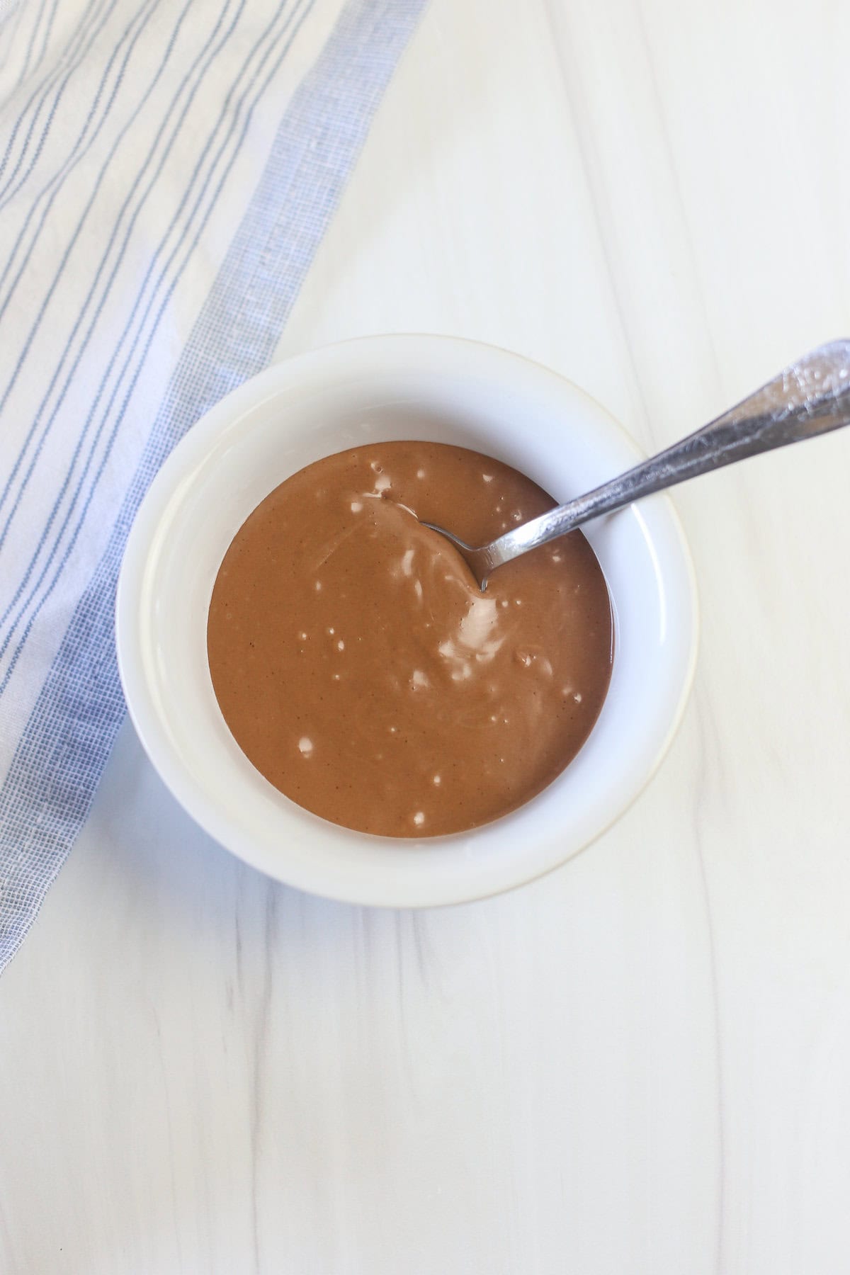 Nutella glaze in a small white bowl with a spoon.