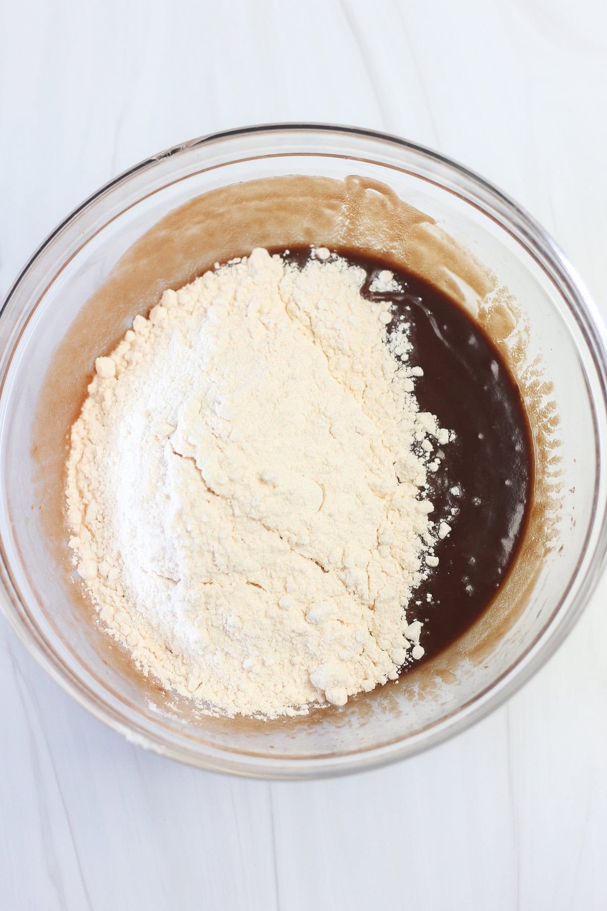 Cake mix on top of the wet ingredients of Nutella cake mix cookies in a mixing bowl.