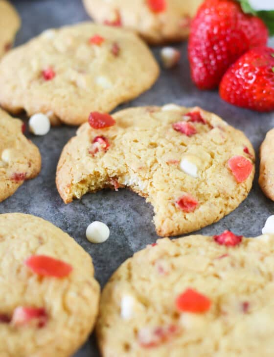 Strawberries and cream cake mix cookies on a gray marble serving platter with a bite missing in the middle cookie.