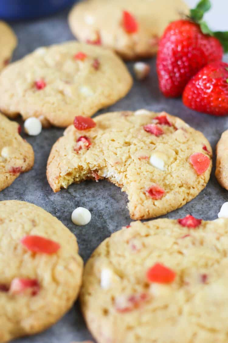 Strawberries and cream cake mix cookies on a gray marble serving platter with a bite missing in the middle cookie.