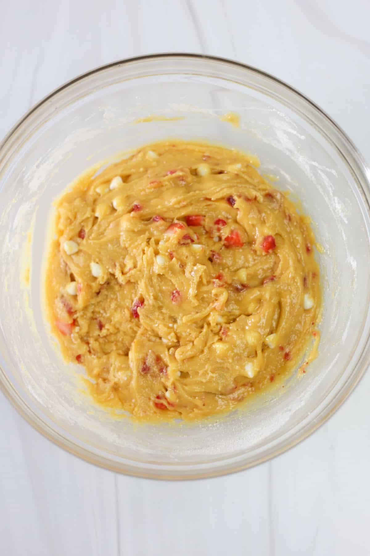 Strawberries and cream cake mix cookie dough in a mixing bowl.