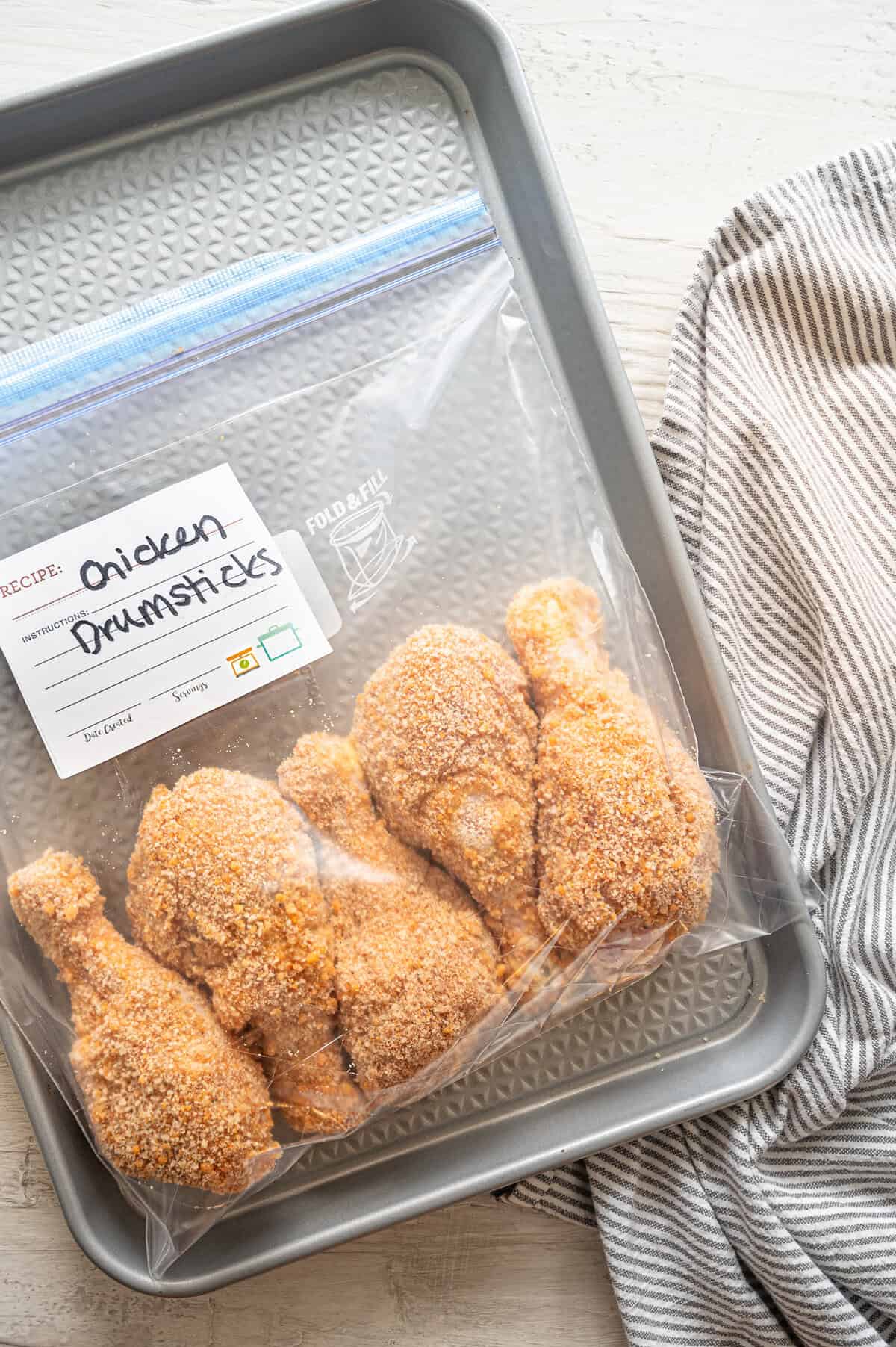 Breaded drumsticks in a freezer-safe bag labeled chicken drumsticks ready for the freezer.