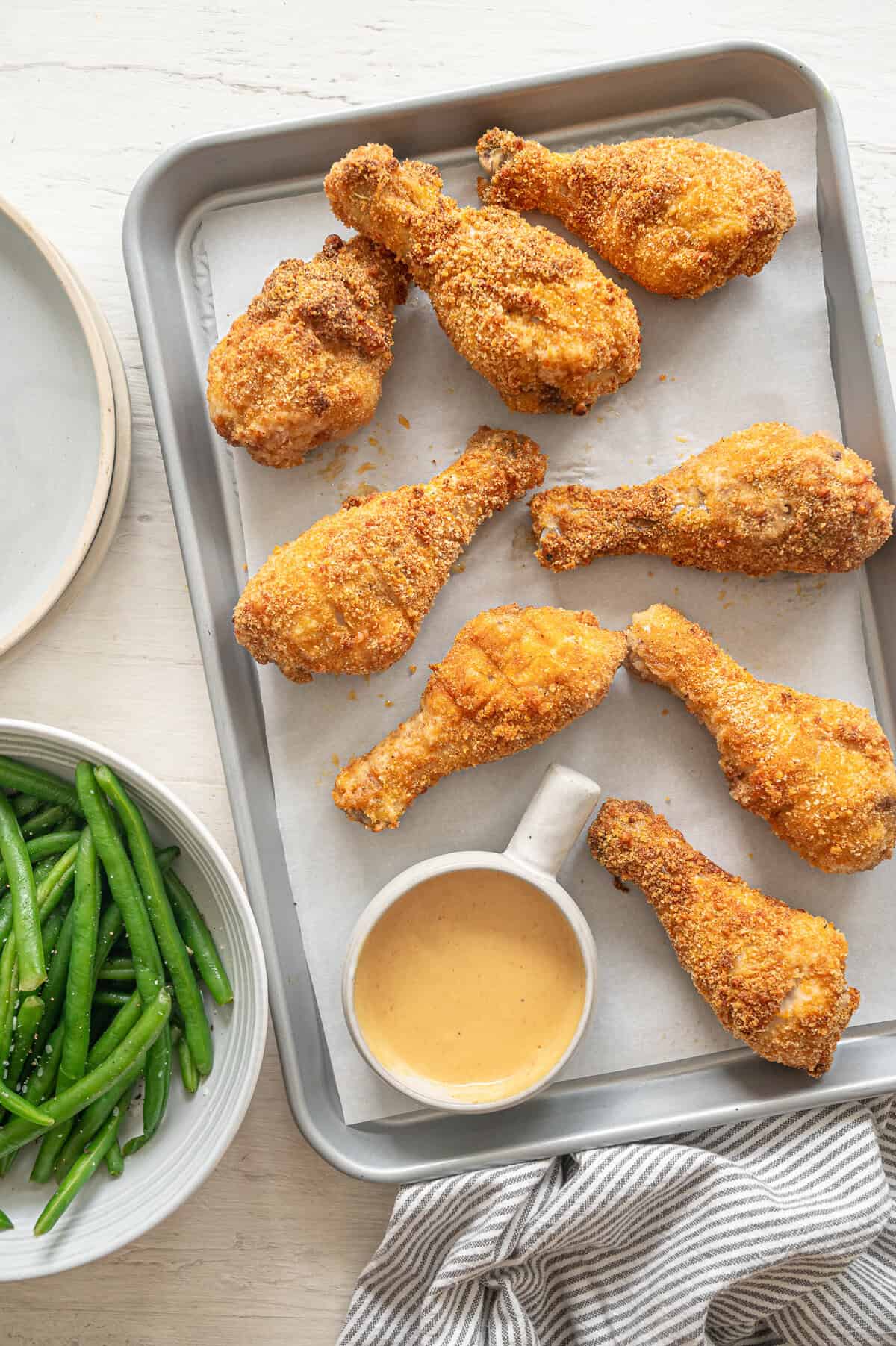 Crispy baked drumsticks on a pan with honey mustard dipping sauce.