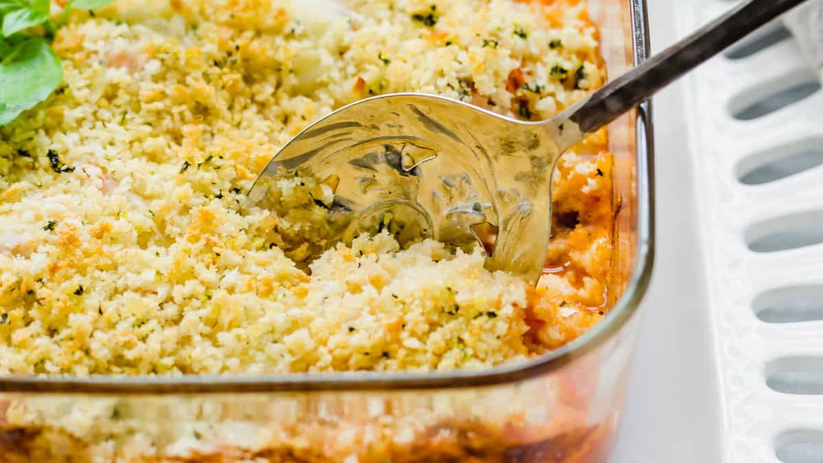 Chicken Parmesan casserole in a glass baking dish with a spoon.