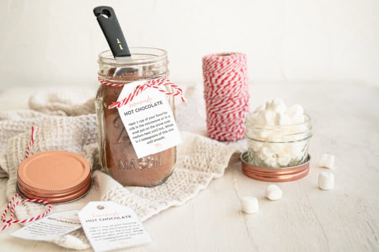 A mason jar of homemade hot chocolate with a gift tag and a smaller mason jar of mini marshmallows next to it.