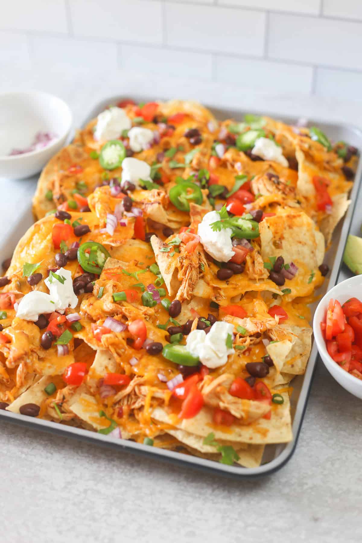 Shredded chicken nachos on a baking sheet.