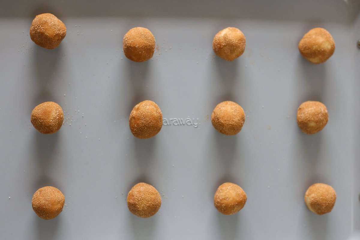 Snickerdoodle cookie dough lined up on a baking sheet ready for the oven.