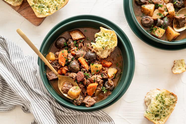 A bowl of beef bourguignon with crusty bread on the side.